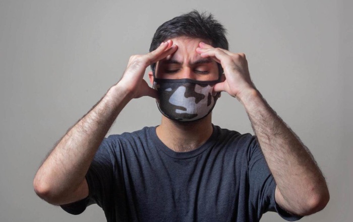 Sarkis Psychology Today image of a man wearing a face mask rubbing his temples in distress PC: Yousaf Usman usman-yousaf-Dd6St65dfYw-unsplash