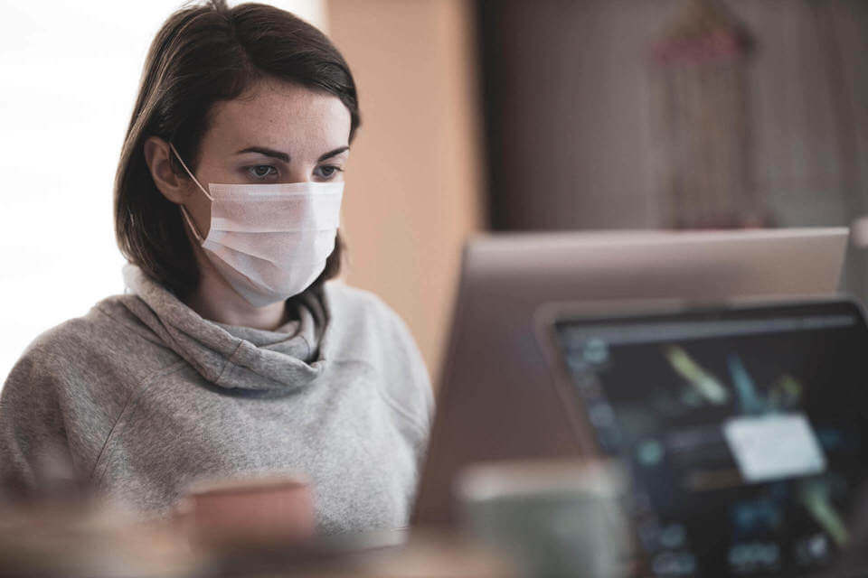Young woman in face mask using a computer - “Expect Increased Anxiety and Depression in College Students” on Psychology Today - article by Stephanie Sarkis, PhD Photo Source: Engin Akyurt on Unsplash