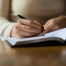Image of a woman's hand holding a pen writing in a journal. For article by Stephanie Sarkis on Psychology Today "Consider Skipping New Year's Resolutions in 2021" PC: ava-sol-JaUn2B6smQs-unsplash