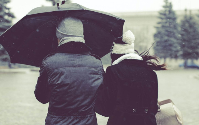 Photo of two people walking away from camera dressed in coats and beanies with and under an umbrella Article info: Signs You Are Trauma-Bonded to Someone on Psychology Today by: Dr Stephanie Sarkis. Photo Credit: pavel-badrtdinov-oHQqaekhPqI-unsplash