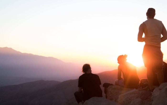 Photo of three hikers on mountaintop at sunrise. Two are seated and one is standing. Post photo for "Why Anxious and Avoidant Attachment Attract Each Other" on Psychology Today by: Dr Stephanie Sarkis.