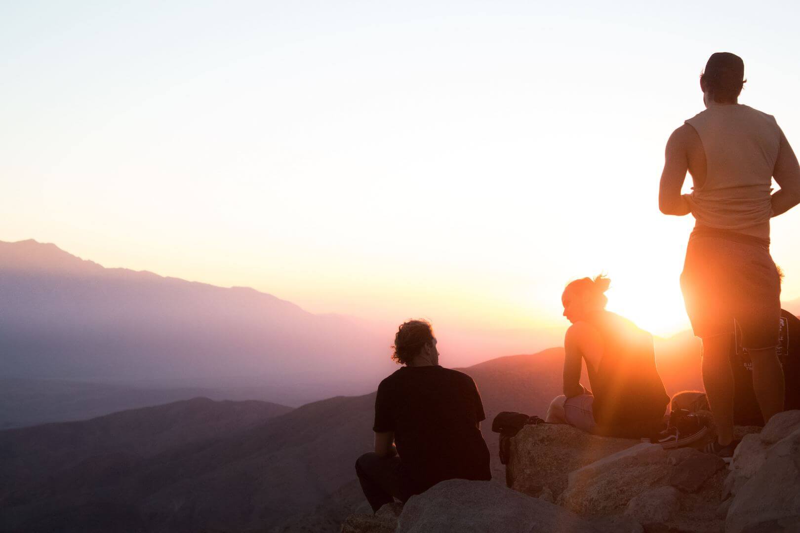 Photo of three hikers on mountaintop at sunrise. Two are seated and one is standing. Post photo for "Why Anxious and Avoidant Attachment Attract Each Other" on Psychology Today by: Dr Stephanie Sarkis.