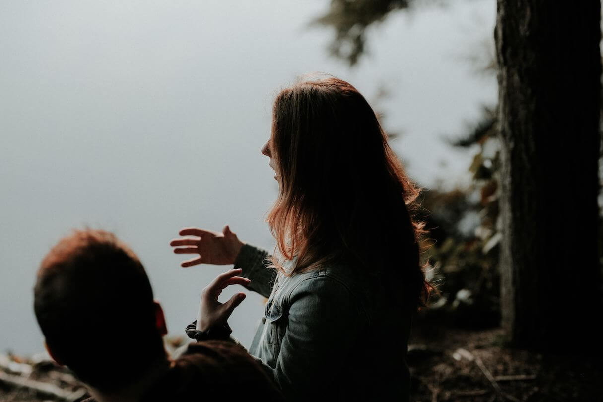 Image of two people in conversation, one gesturing with her hands, sitting near several trees. Post photo for "How Cognitive Biases Impact Our Relationships" on Psychology Today by: Dr Stephanie Sarkis.