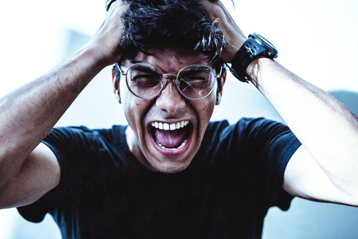 Image of a man with glasses, one lens cracked, with both hands on his head yelling in frustration. Post photo for "The Dire Consequences of Having a Narcissistic Parent" on Psychology Today by: Dr Stephanie Sarkis.